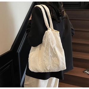 Close-up of white lace embroidery tote bag with oversized shoulder strap bow detail