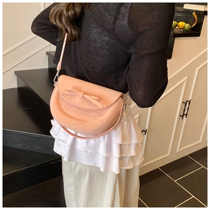 Gros plan d'un sac besace rose avec noeud décoratif et détails de quincaillerie argentée