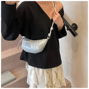 Detail showing knotted shoulder strap and silver patent leather on crescent bag