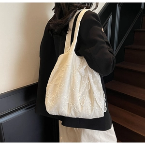 Detail of white lace embroidery tote bag showing delicate floral patterns and shoulder strap