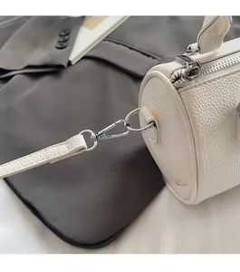 Close-up of white lychee leather handbag with silver lobster clasp and D-ring detail