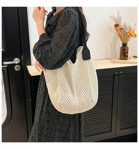 Detail of off-white knitted tote bag with large hollow weave and black leather straps