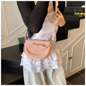 Détail d'un sac à main rose avec nœud décoratif et bandoulière réglable pour femme