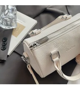 Detail of silver zipper and lychee textured cream leather on the cylindrical bag