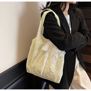 Detail of floral embroidery and a white lace bow on the yellow linen shoulder bag