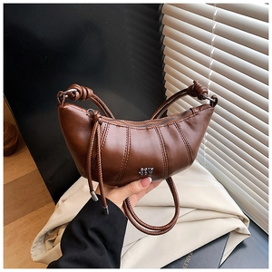 Close-up of dark brown leather croissant bag with knotted handle and metal SSW logo