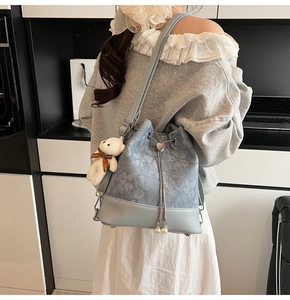 Detail of floral drawstring bucket bag featuring pearl pendant and cute bear charm