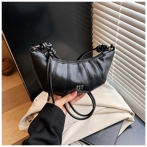Detail of black pleated leather dumpling bag with metal logo and knotted strap handle