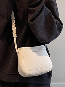 Minimalist beige crossbody bucket bag with textured leather and woven shoulder strap