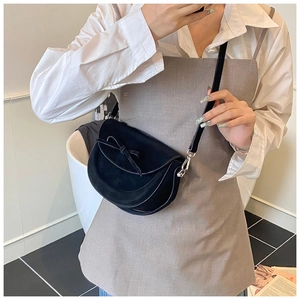 Détail d'un sac besace noir mat avec un nœud décoratif et une boucle en métal argenté