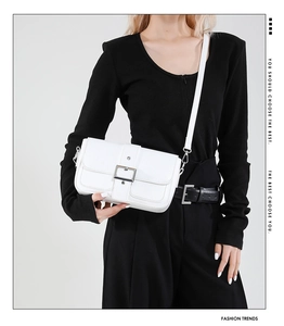 Détail du sac à bandoulière blanc minimaliste avec boucle argentée et texture en cuir