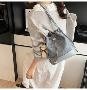 Detail of floral jacquard bucket bag with drawstring closure and cute bear pendant