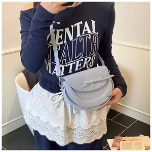 Détail d'un sac selle bleu clair avec un nœud décoratif et une bandoulière réglable