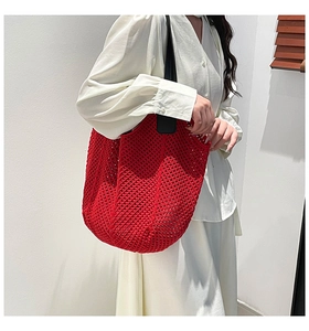 Close-up of red crochet tote bag featuring hollow mesh design and black contrast handles