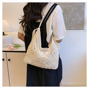 Dettaglio borsa a spalla all'uncinetto con trama a maglia traforata e nappa decorativa
