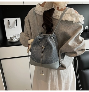 Detail of grey floral backpack with heart-shaped buckle and pearl drawstring tassel