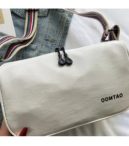 Detail of white dumpling bag with colored striped strap and soft fabric texture