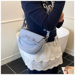 Détail d'un sac besace bleu clair avec nœud décoratif et bandoulière réglable