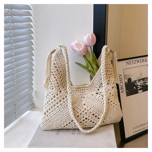 Dettaglio borsa shopper beige all'uncinetto con motivi traforati e nappe decorative