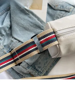 Detail of cream leather bag with red, blue and white striped wide fabric shoulder strap
