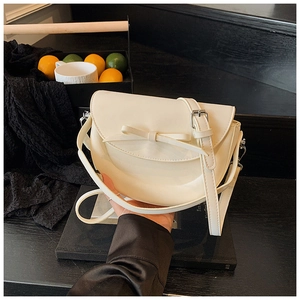 Détail du sac selle blanc crème avec nœud et finition mate lisse de haute qualité