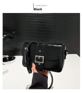 Détail du petit sac bandoulière en cuir noir brillant avec boucle argentée et sangle réglable