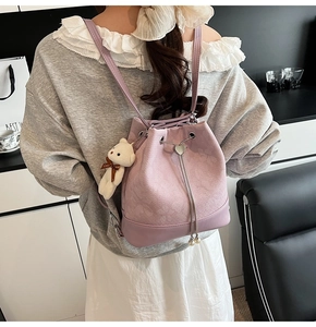 Detail of lilac bucket bag with plush bear charm and metallic chain on female model