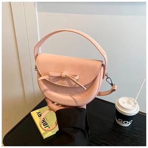 Vue détaillée du sac selle rose avec décoration de nœud et ferrures métalliques argentées