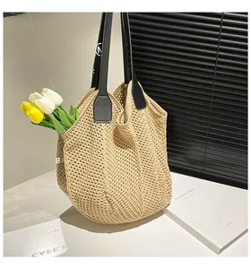 Close-up detail of knitted tote bag with hollow pattern and black straps with tulips