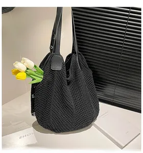 Detail of a black knit crochet tote bag with leather handles and hollow woven texture