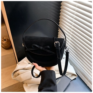 Détail du sac selle en daim noir avec nœud élégant et bandoulière réglable pratique