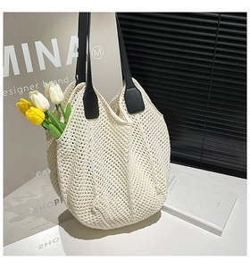 Detailed macro view of the cream woven knit tote bag texture and durable black faux leather straps