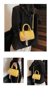 Detail of yellow lychee leather barrel bag with plush bear charm and metallic hardware