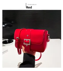 Détail d'un sac à bandoulière en cuir verni rouge avec boucle argentée et sangle réglable