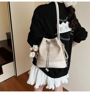 Close-up of floral jacquard bucket bag with pearl drawstring and bear plush charm