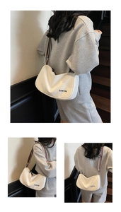 Detail view of white hobo bag featuring logo print and colorful striped shoulder strap