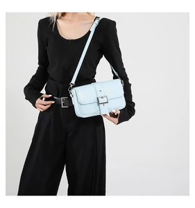 Gros plan du sac bandoulière en cuir bleu clair avec boucle argentée et texture lisse