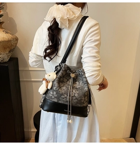 Detail of floral drawstring bucket bag with bear pendant and pearl tassel on model