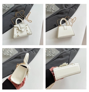 Makroaufnahme der weißen quadratischen Handtasche mit goldener Kette und Nietendetails