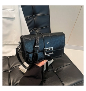 Détail d'un sac d'épaule en cuir verni noir brillant avec boucle métallique argentée