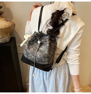 Close-up of jacquard bucket backpack with drawstring, silver heart pendant, and plush bear