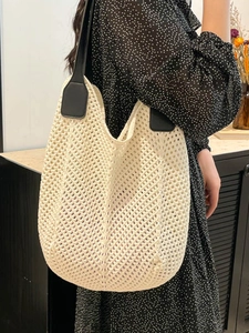 Minimalist cream knit tote bag with black leather straps shown in a lifestyle setting
