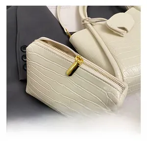 Detail of cream crocodile embossed leather bucket bag with premium gold zipper and pouch