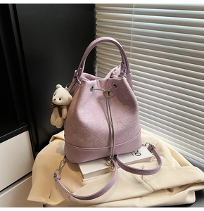 Detail of purple tweed bucket bag with heart metal buckle, pearls, and a bear charm