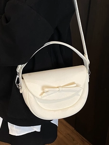 Sacoche crème avec nœud portée par un mannequin en sac à bandoulière élégant