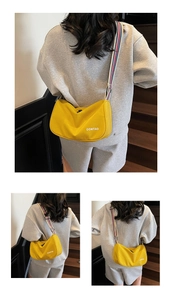 Detail of yellow canvas dumpling bag with striped wide strap on model in stair scene