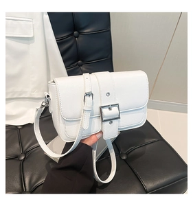 Détail d'un sac bandoulière blanc en cuir texturé avec boucle argentée et sangle réglable