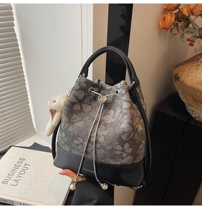 Detail of floral bucket bag with heart metal buckle and pearl pendant on textured canvas