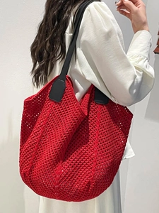 Red oversized crochet tote bag with black leather straps shown on model's shoulder