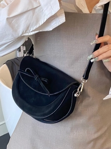 Sacoche selle en daim noir avec noeud élégant porté à l'épaule par un mannequin